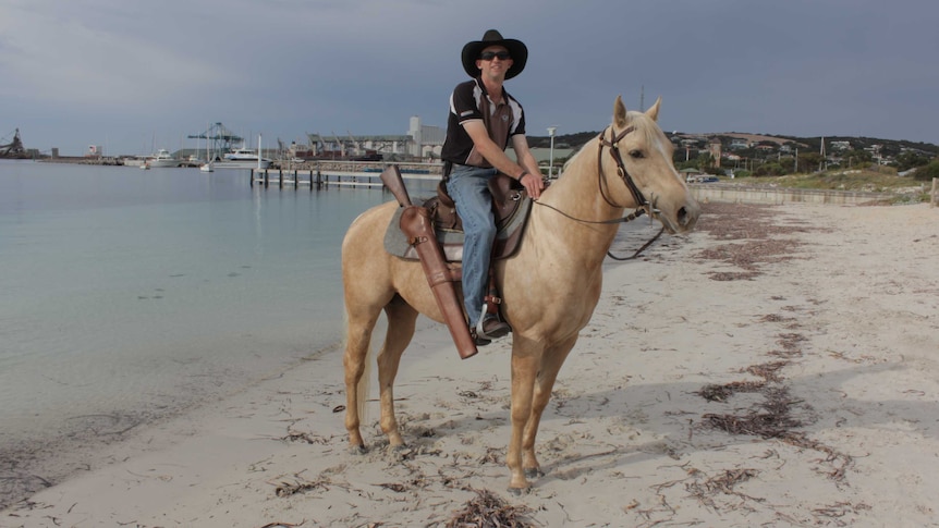 A man sits on a horse at the beach