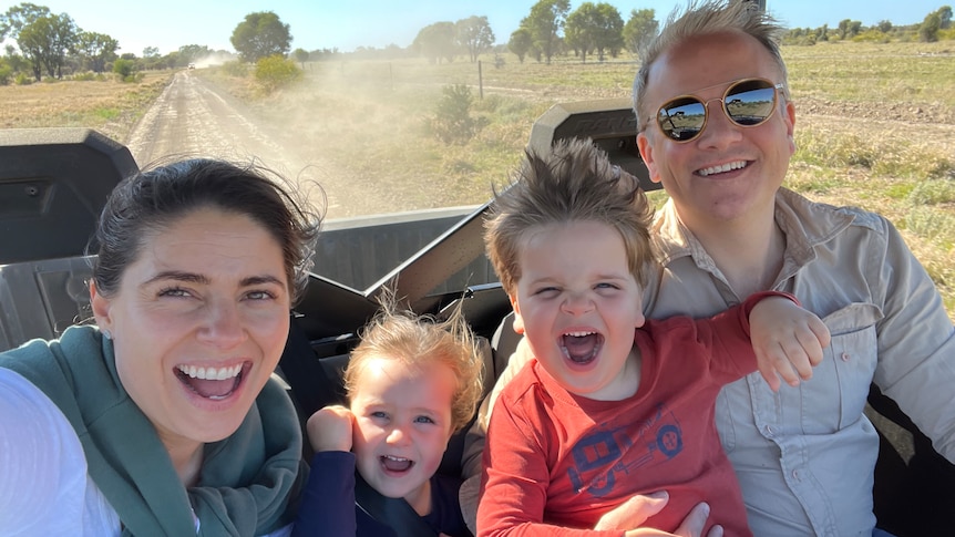 A young family in a 4x4 on a dusty road.