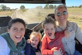 A young family in a 4x4 on a dusty road.