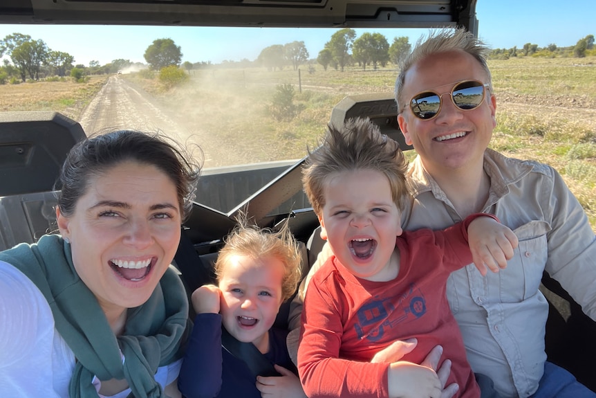 A young family in a 4x4 on a dusty road.