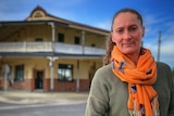 A woman standing outside with a historic pub in the background.