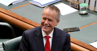 Bill Shorten sits on a chair and smiles.