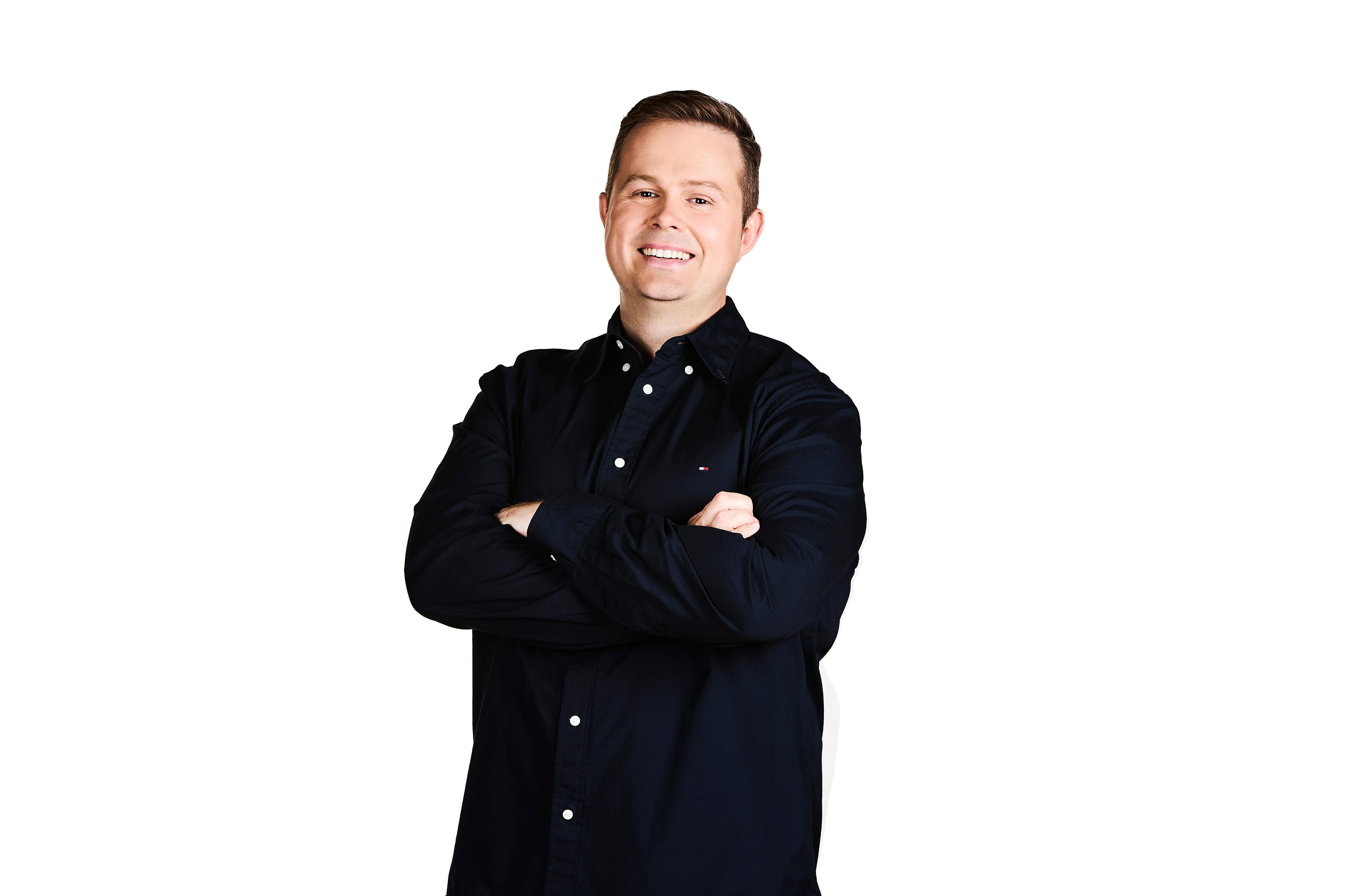 A man standing with arms folded smiling 