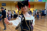 A woman in a black and gold national custume dances in a hall
