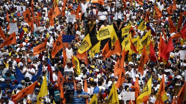 Thousands of people carrying gold and orange flags march in Caracas