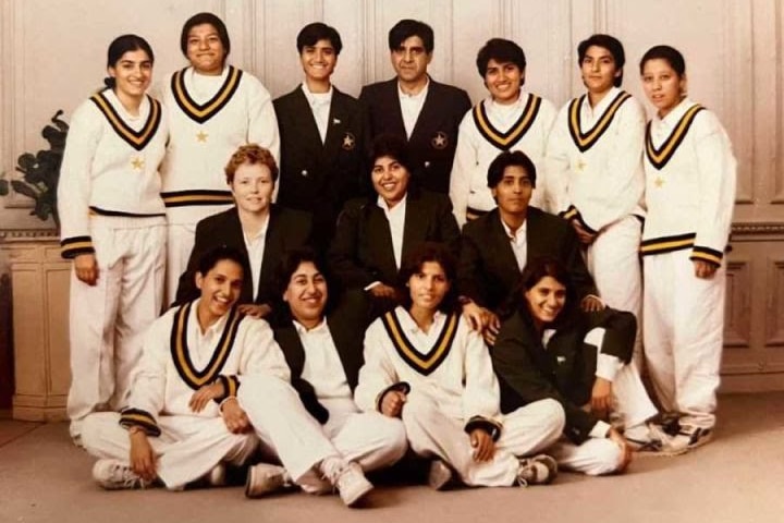 Pakistan players sit and stand in three rows as they pose in their cricket whites and dark green blazers