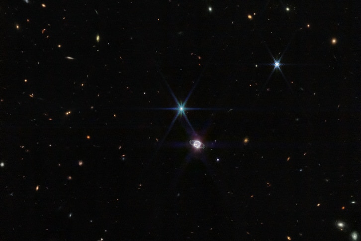 A wide-angle image of neptune and Triton againsta black galaxy. 