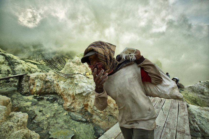 An Indonesian sulphur miner exists the danger zone as quickly as possible.