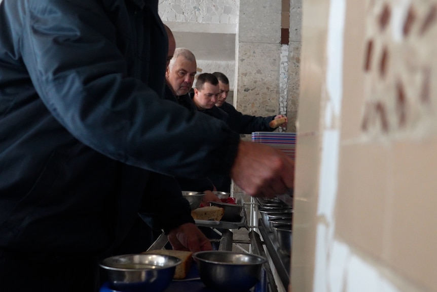Русские военнопленные стоят в очереди, чтобы подать еду в столовую.