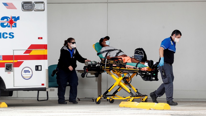 Paramedics wheel a patient on a gurney into a hospital.