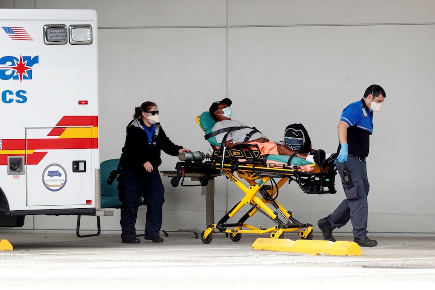 Paramedics wheel a patient on a gurney into a hospital.