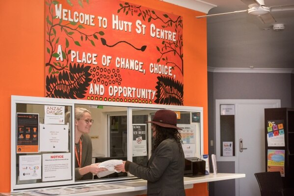 A client in a hat speaks to a woman at reception at the Hutt Street homeless centre in Adelaide