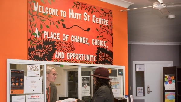 A client in a hat speaks to a woman at reception at the Hutt Street homeless centre in Adelaide