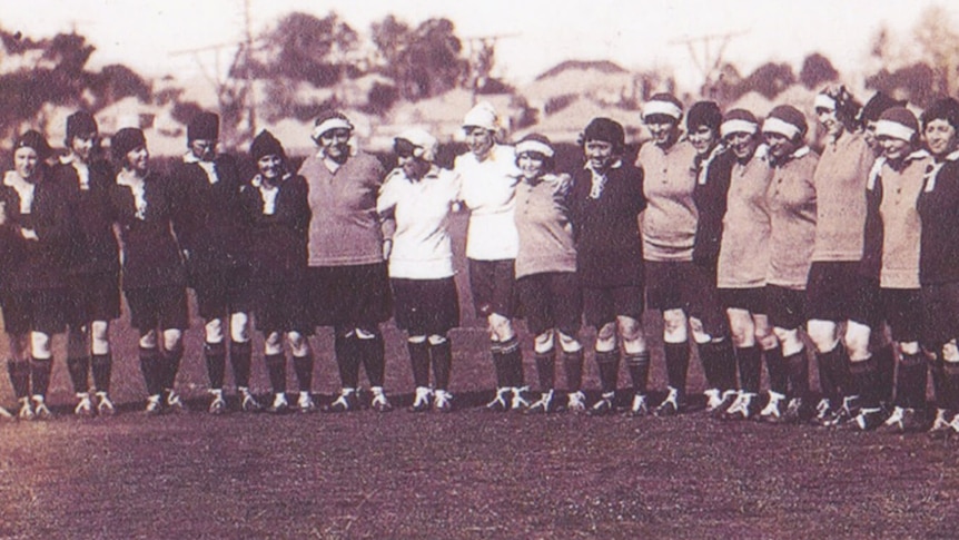 Women stand together in a line in a black and white football shirts