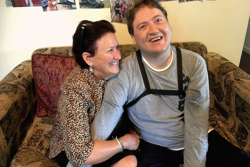 A man in his twenties gets a hug from his mother