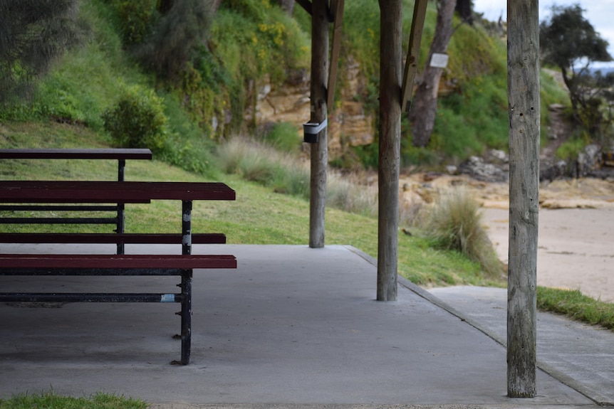 A beach shelter with two benches.