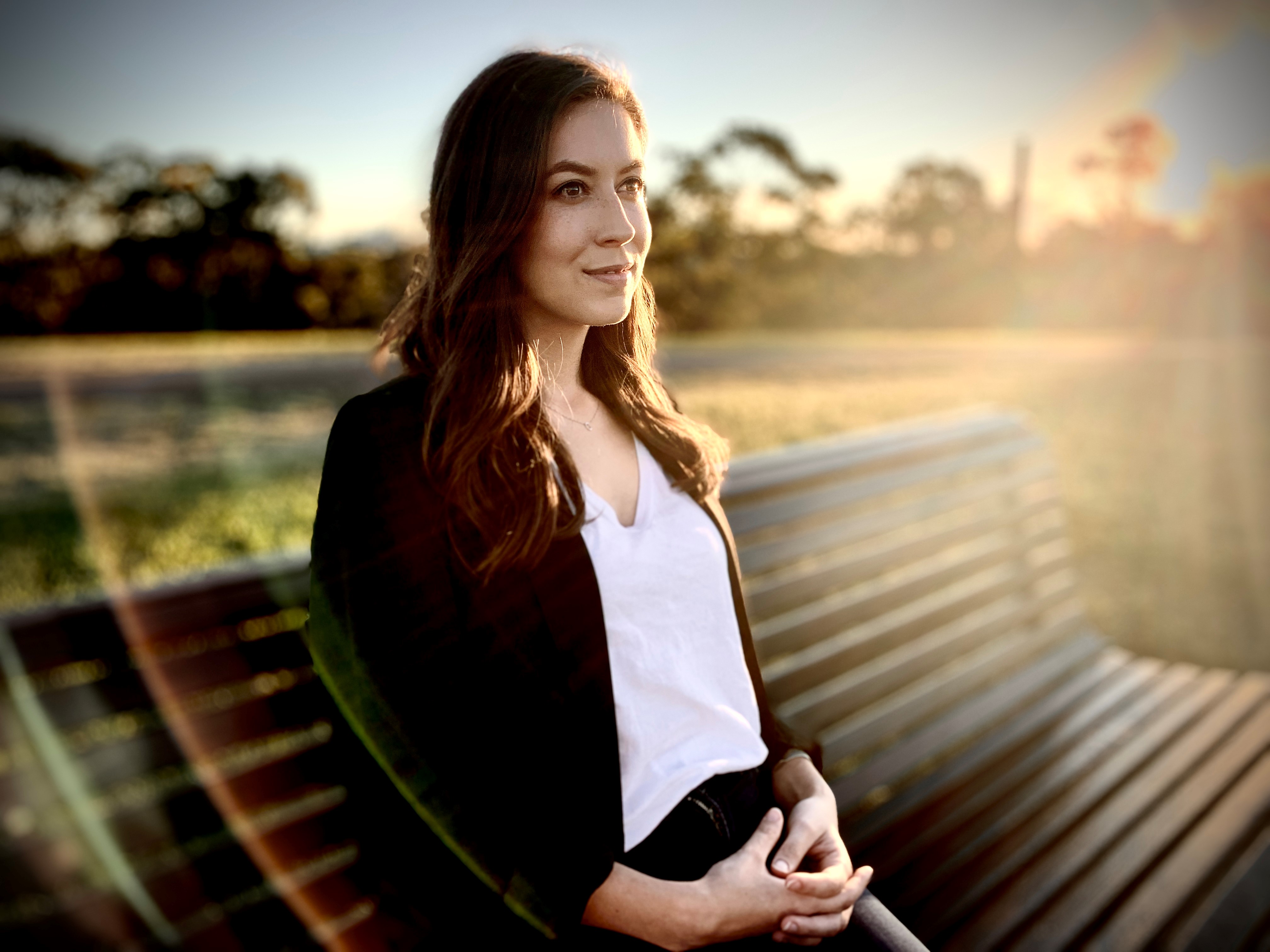 Sharlie Raymond sits on a park bench and looks into the distance 