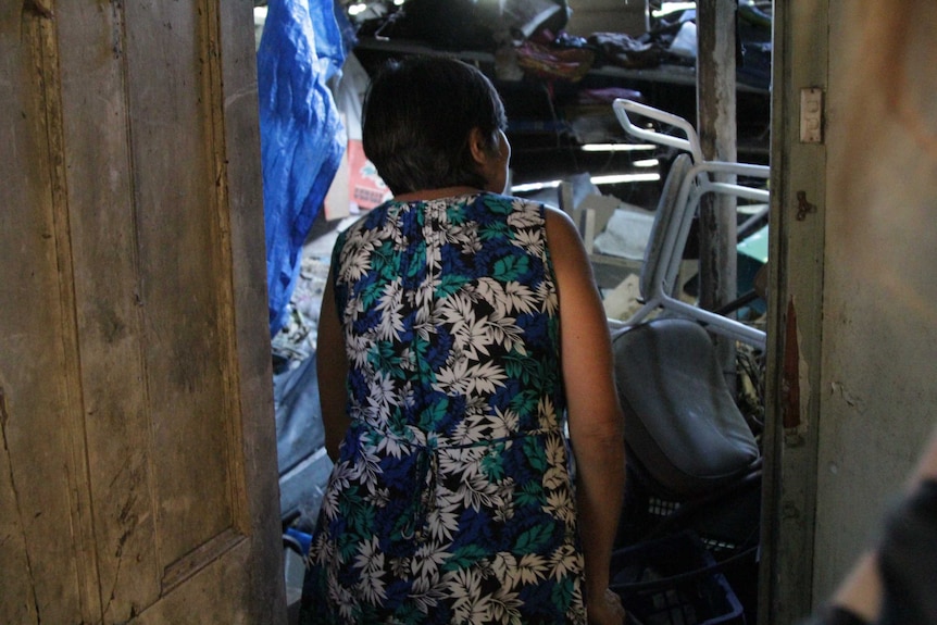 Woman peeking into the door of a cluttered house.