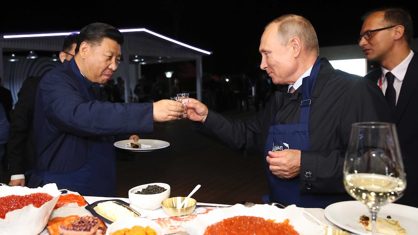Vladimir Putin and Xi Jinping toast each other with vodka glasses