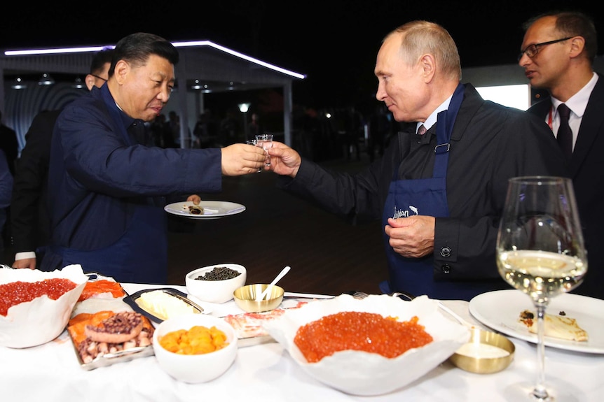 Vladimir Putin and Xi Jinping toast each other with vodka glasses