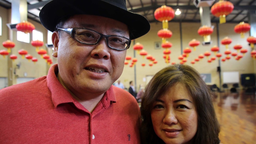 Close-up of Noel and Sandra Ong standing in a hall decorated with Chinese lanterns.