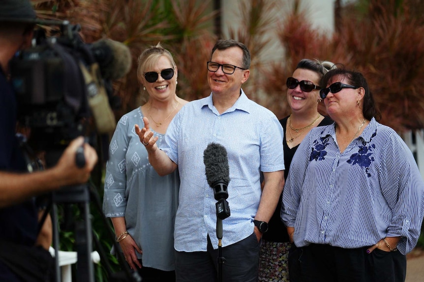 Four of Barbara Francis's children smile and laugh at the camera standing outside court.