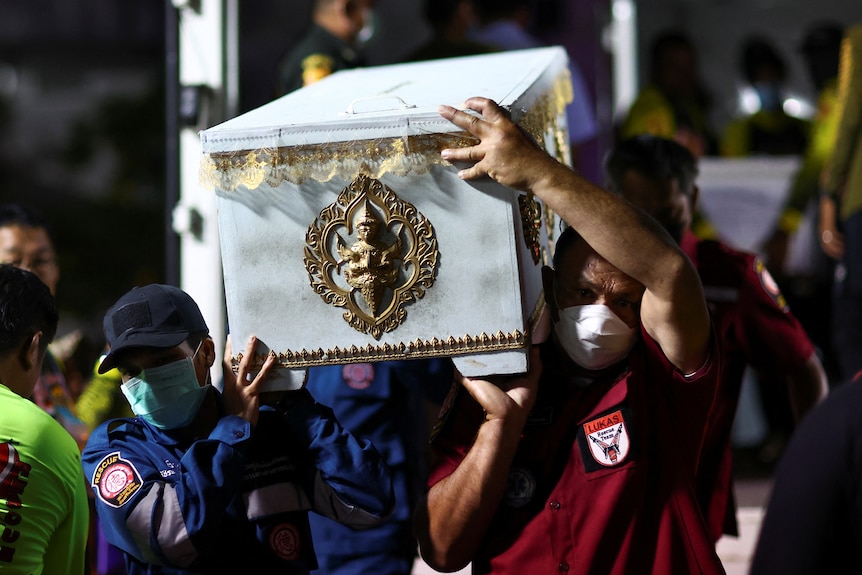 Rescue workers carry a coffin containing the body of a victim.