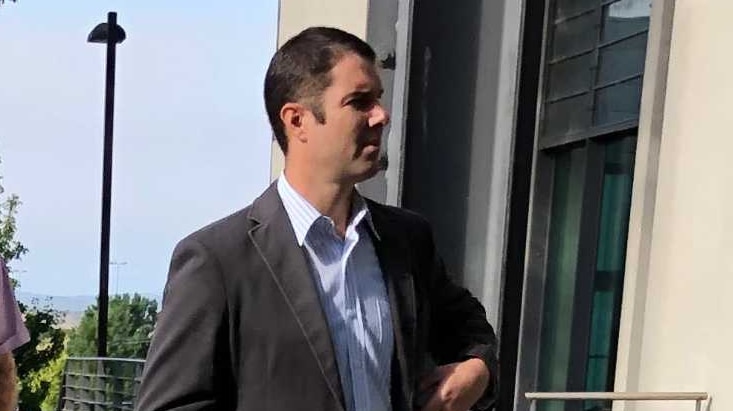 A man dressed in a suit enters a courthouse.