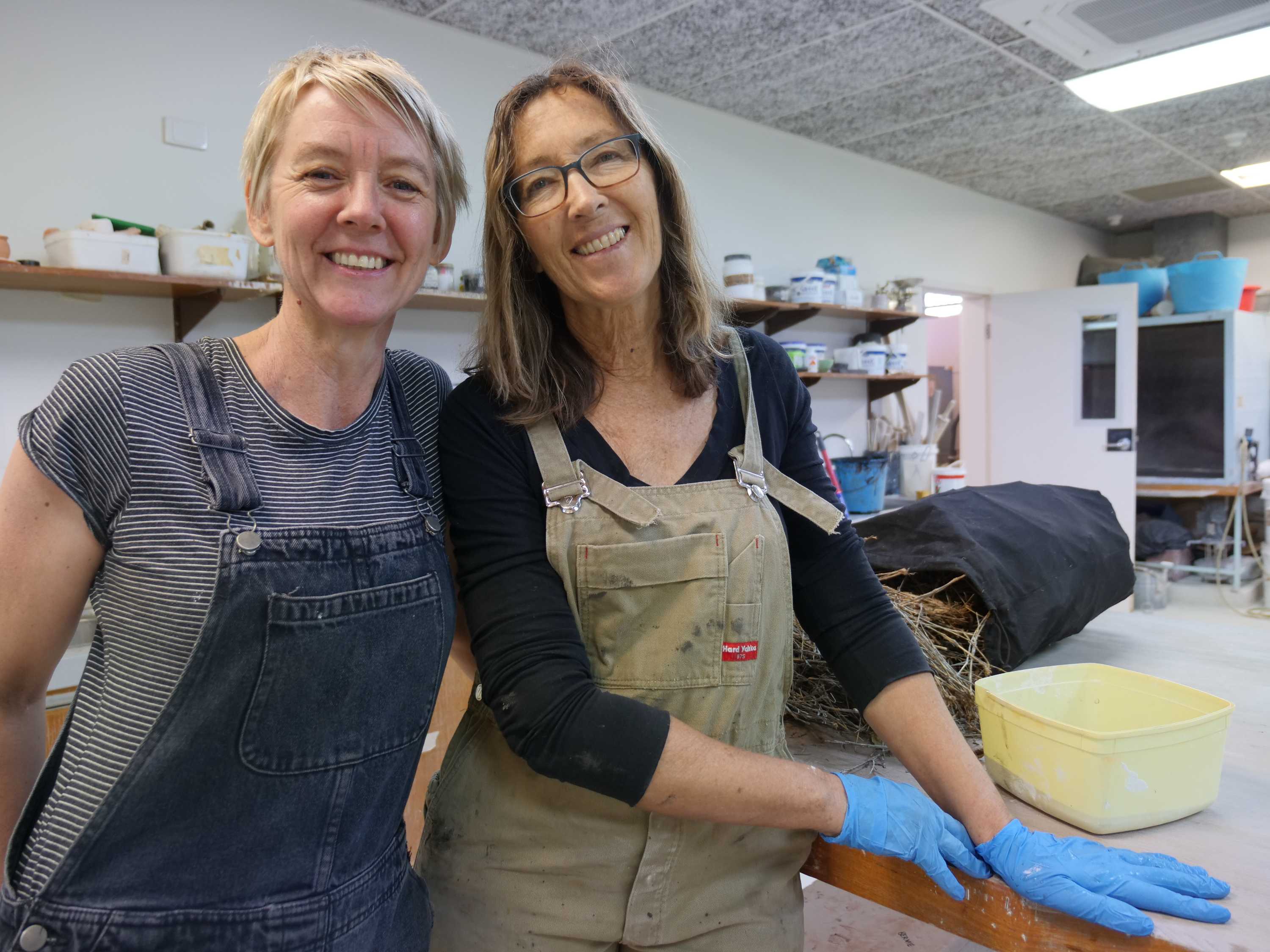 two women standing next to each other in a workshop