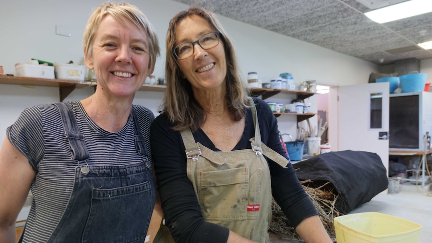 two women standing next to each other in a workshop