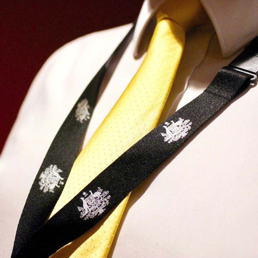 A man wears a lanyard with the Australian Government coat of arms on it.