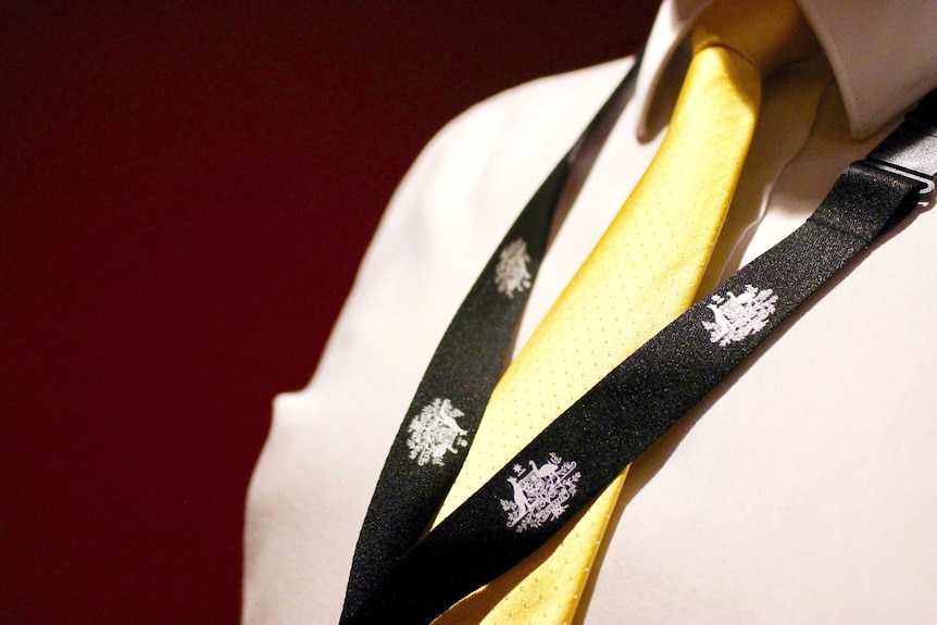 A man wears a lanyard with the Australian Government coat of arms on it.