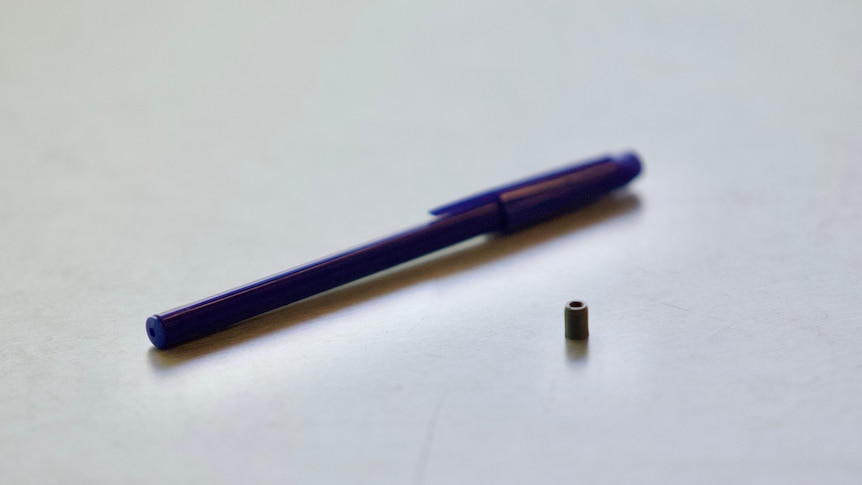 A 3D printed replica of a missing radioactive capsule next to a pen on a table.