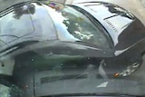 A black car seen from above through a windscreen, debris flying.