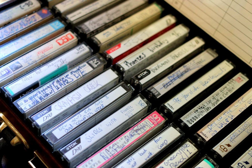 A collection of cassette tapes rest in a suitcase.