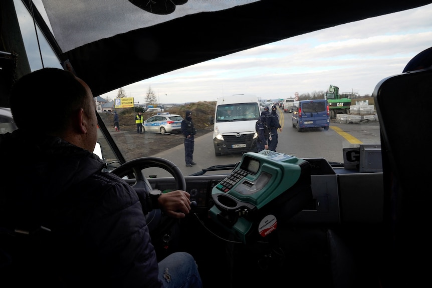 a view of heavy traffic on a road in Poland from over the shoulder of a bus driving driving refugees