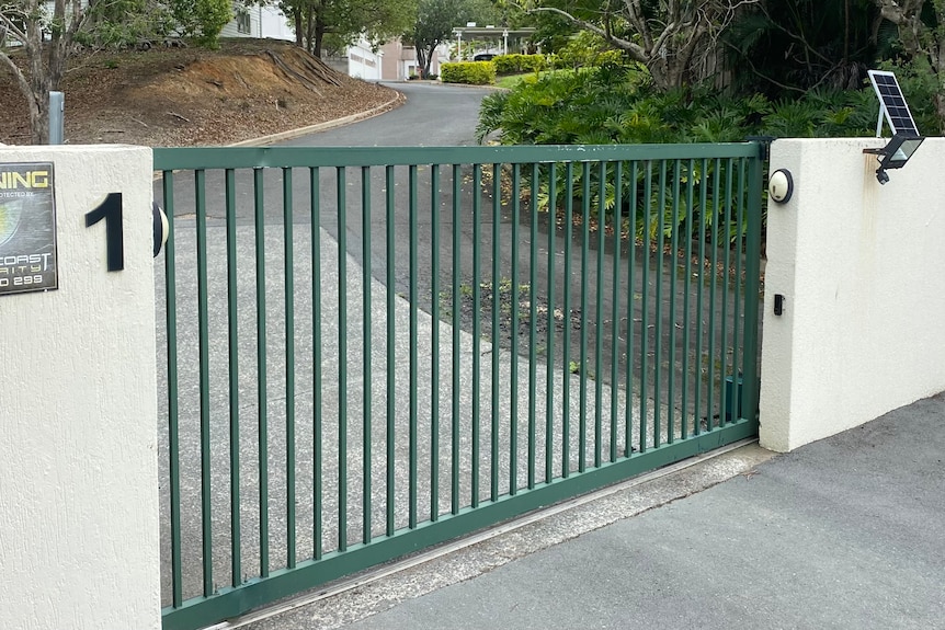a green sliding security fence at the entrance to a large property