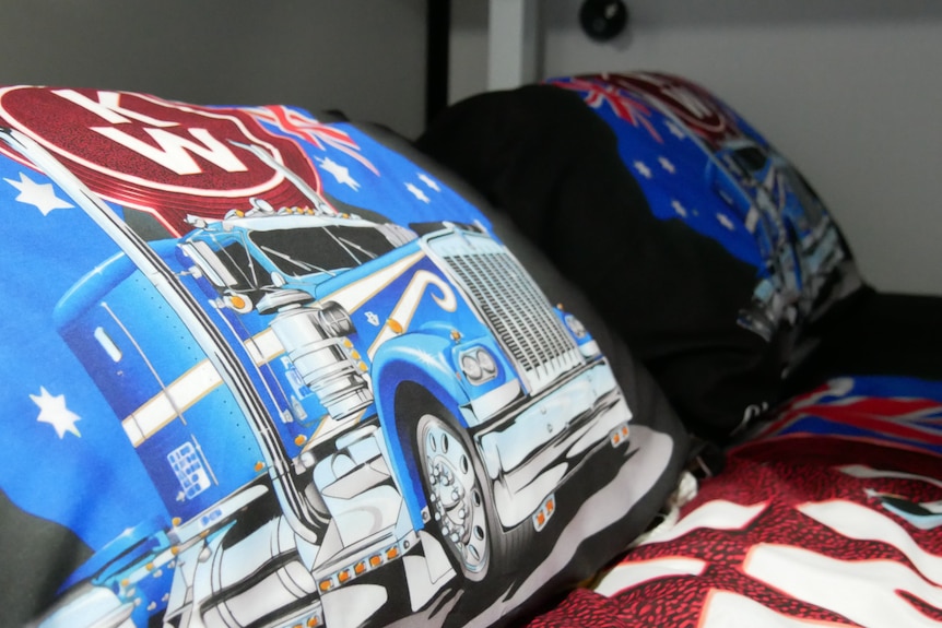 Bed pillows with blue trucks on them. 