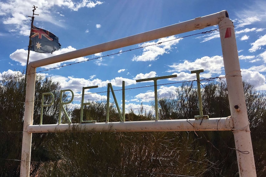 Home made sign using steel, painted white on edge of fence with Australian flag in background