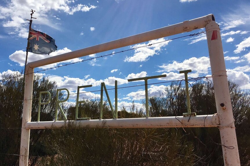 Home made sign using steel, painted white on edge of fence with Australian flag in background