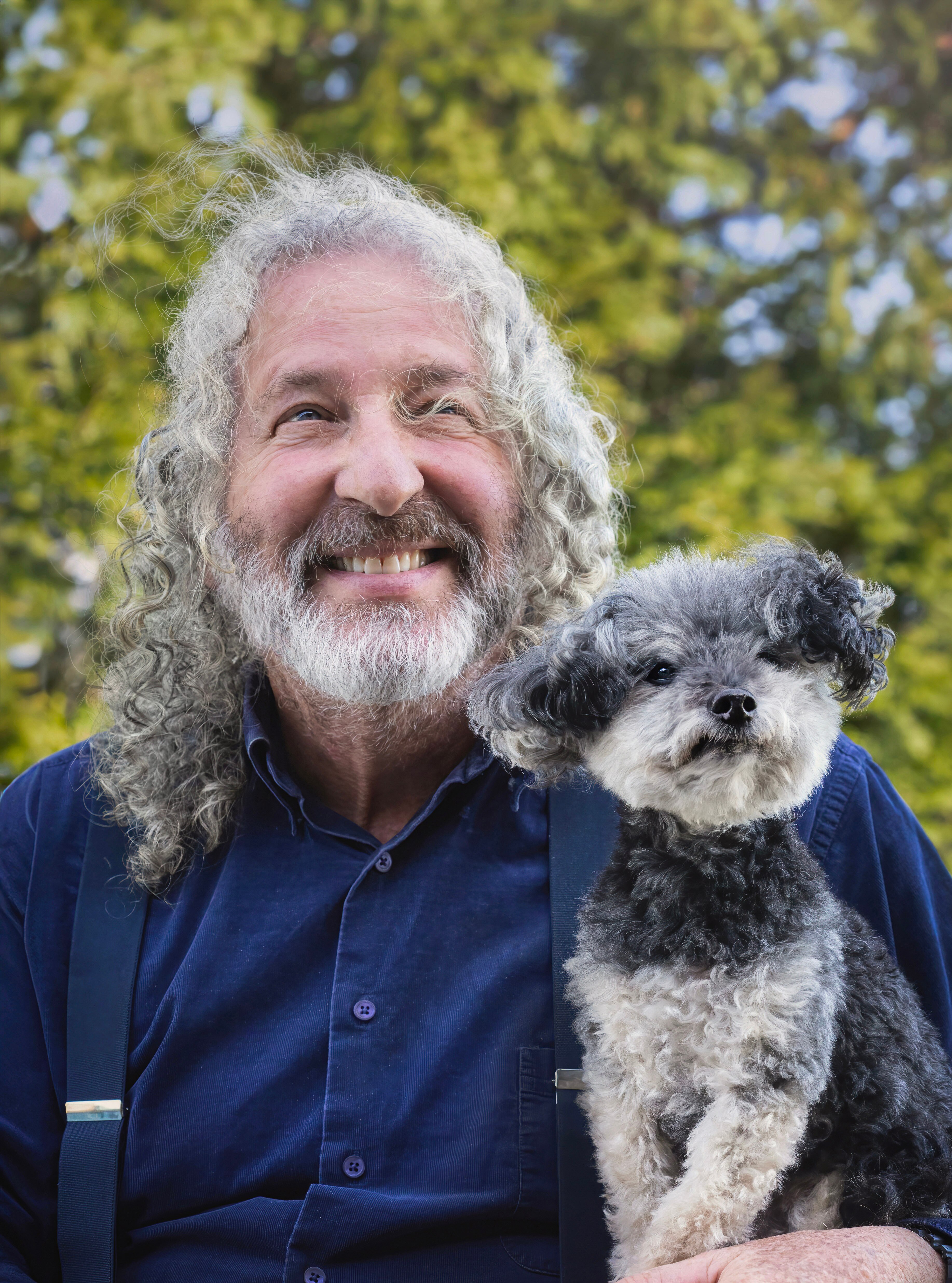 A man taking a photo with his dog. They both have greyish white beards