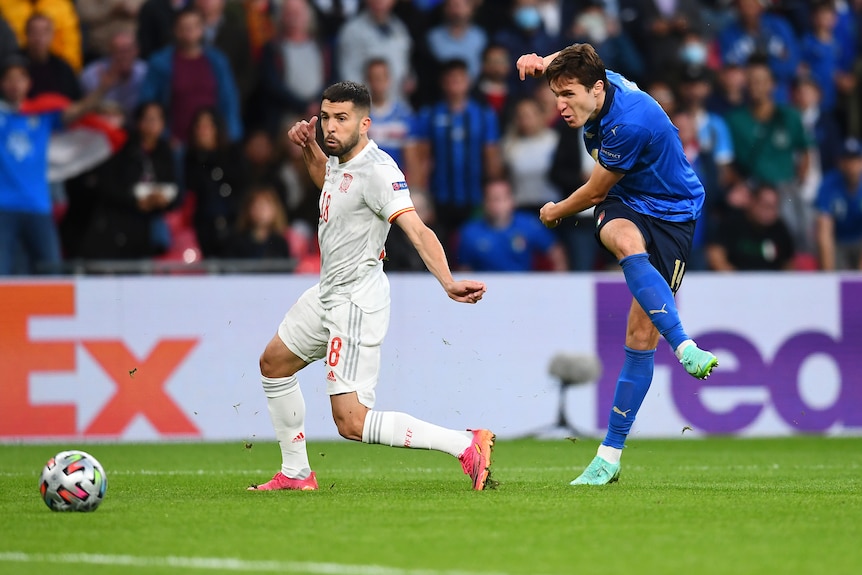 An Italian striker bends his leg around the ball as he shoots for goal in the Euro 2020 semi-final