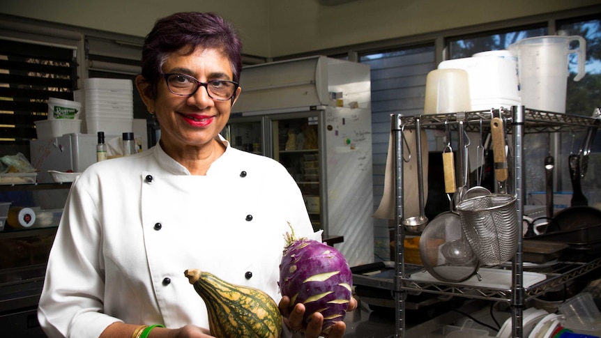 Amorelle Dempster stands in her kitchen holding vegetables.