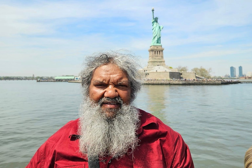 a man stands near the Statue of Liberty 