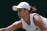 Ashleigh Barty puffs her cheeks while at full stretch to return a shot on the forehand at Wimbledon