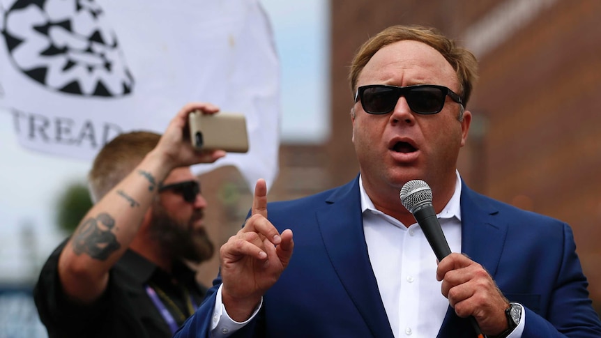 A man speaking into a microphone at a rally.