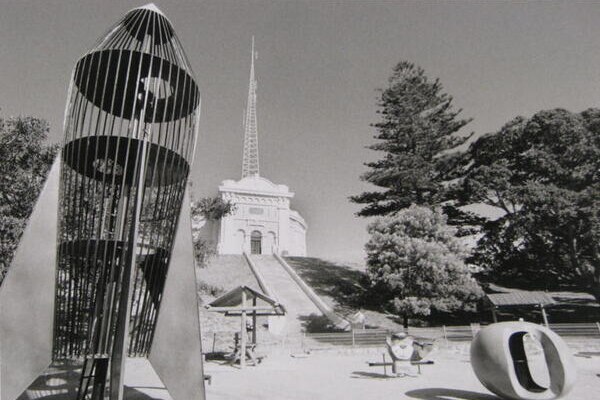 A black and white photo of a rocket playground with a hill in the background