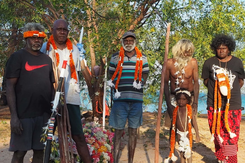 Community leaders from clans in Elcho Island stand on a beach.