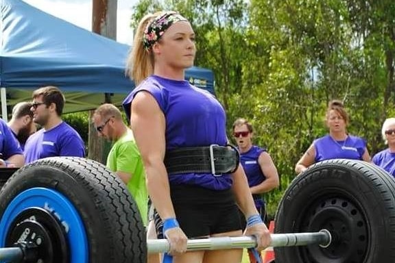 Woman lifting weights with tyres.
