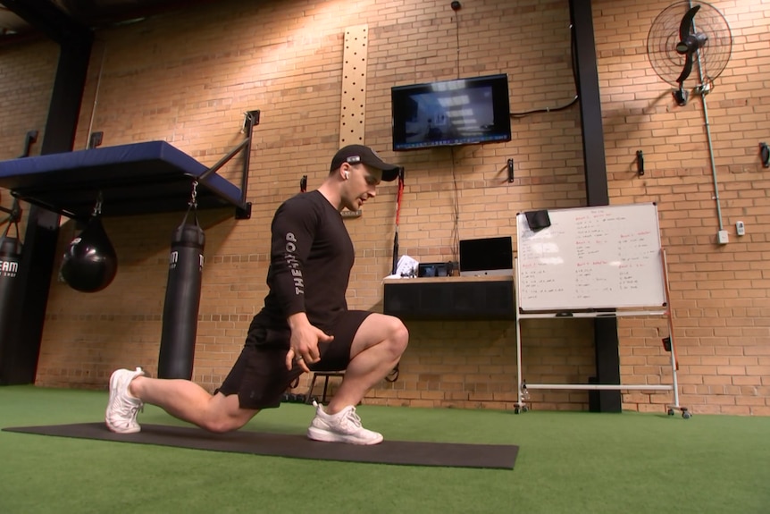 Brad Cunningham stands in front of his computer in his gym, hands behind his back.